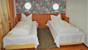 two beds in a room with white sheets at Hotel Sonne in Sibiu
