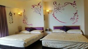 2 camas en una habitación con pinturas en la pared en Qinbianlu B&B, en Jiufen