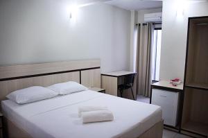 a bedroom with a white bed with two towels on it at HOTEL VINTE UM in Ceilândia