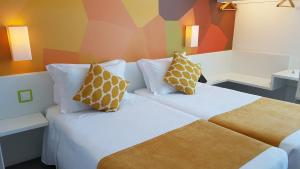 a hotel room with a bed with two pillows at Hotel 3K Faro Aeroporto in Faro +28 photos