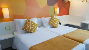 a hotel room with a bed with two pillows at Hotel 3K Faro Aeroporto in Faro