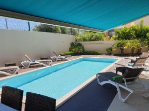 a large swimming pool with chairs and a blue umbrella at Luxury Villa Corcovada Nicole with privat heated pool in Albufeira
