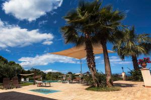 two palm trees and chairs next to a pool at Tenuta Santa Tecla in Acireale