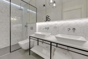 a white bathroom with two sinks and a toilet at Equus Sopot Apartments in Sopot