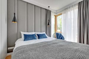 1 dormitorio con 1 cama grande con almohadas azules en Equus Sopot Apartments en Sopot