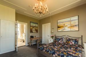 1 dormitorio con cama y lámpara de araña en Pastorie Stella Marie, en Oudeschild