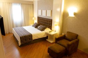 a hotel room with a bed and a chair at Bristol International Guarulhos in Guarulhos