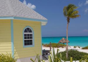 a yellow building on the beach with a palm tree at Paradise Bay Bahamas in Farmerʼs Hill