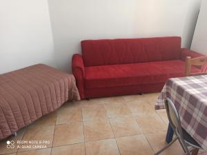 een rode bank en een bed in een kamer bij Akti Miaouli Holiday Home in Vári