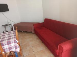 een woonkamer met een rode bank en een bed bij Akti Miaouli Holiday Home in Vári