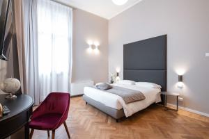 una camera con un grande letto e una sedia rossa di Hotel Palazzo Martinelli Dolfin a Venezia