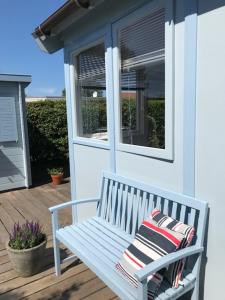 un banc blanc assis sur une terrasse couverte avec une fenêtre dans l'établissement Vakantiehuisje in Ouddorp dichtbij het strand, à Ouddorp