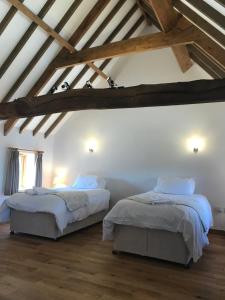 two beds in a room with white walls and wooden beams at The HopBarn in Hockerton