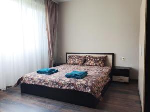 a bedroom with a bed with two blue pillows on it at Апартамент БОНИТА in Haskovo