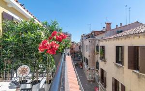 a balcony with red flowers on a city street at Grifoni Boutique Hotel in Venice