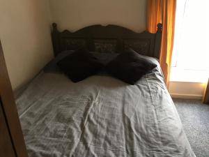 a bed with black pillows on it in a bedroom at Pantyrathro International Hostel in Carmarthen