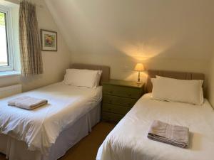 2 camas individuales en una habitación con ventana en Far Hill Cottage, en Wyck Rissington