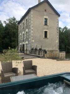 a building with chairs and a pool in front of it at Moulin de la Chevriere in Saché