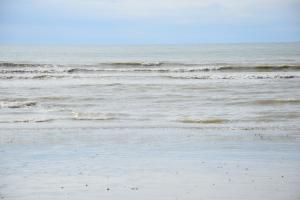 a sandy beach with waves in the ocean at Ces jours en baie Le vue mer in Cayeux-sur-Mer