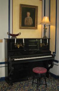 a piano in a room with a portrait of a boy at Hôtel Les Maréchaux in Auxerre