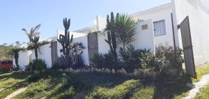 a white house with plants and a fence at A Taberna - chalés in Alto Paraíso de Goiás