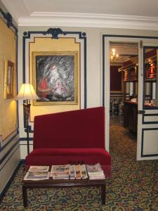 Hôtel Les Maréchaux في أوكسير: غرفة معيشة مع أريكة حمراء وطاولة