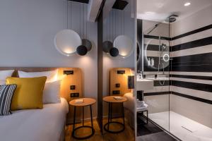 a bedroom with a bed and two stools next to a shower at Hôtel Villa KOEGUI Bayonne in Bayonne +37 photos