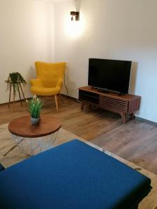 a living room with a television and a chair at Creek Inn, Contactless Check-in in Glanbrücken