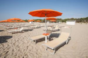 een stel stoelen en parasols op een strand bij Masseria Macchia & Relais San Pio in Marina di Pisticci