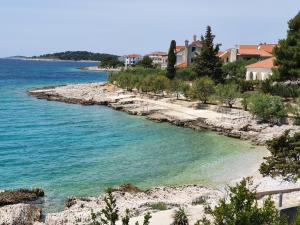 une plage d'eau bleue et des maisons en arrière-plan dans l'établissement Apartmani Mistral, à Rogoznica