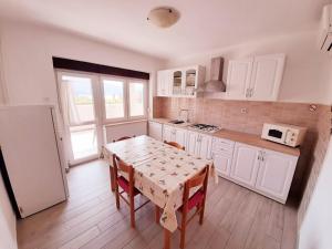 een keuken met een tafel met stoelen en een koelkast bij Apartments Mužić Cres II in Cres