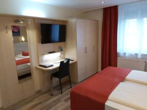 a hotel room with a bed and a desk with a television at Appartement Aragia in Klagenfurt