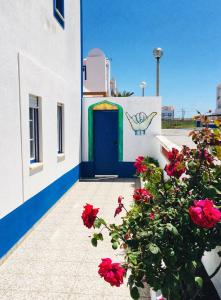 a building with a blue door and red flowers at Baleal GuestHouse in Baleal