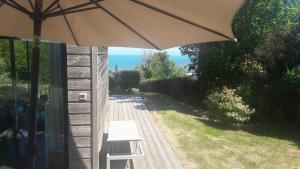 een patio met een bank en een parasol bij Le petit Zeph in Varengeville-sur-Mer