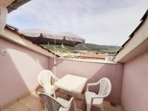 a table and chairs on a balcony with an umbrella at Apartments Mužić Cres in Cres