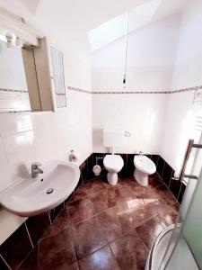 La salle de bains blanche est pourvue de toilettes et d'un lavabo. dans l'établissement Apartments Mužić Cres, à Cres