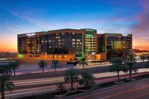 a large building with palm trees in front of a street at Voco - Riyadh by IHG in Riyadh