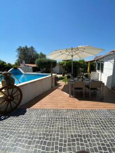 een patio met een tafel en een parasol naast een zwembad bij Casa de Campo in Silveiras