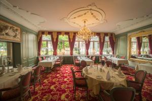 una sala da pranzo con tavoli, sedie e lampadario a braccio di Häcker's Fürstenhof a Bad Bertrich