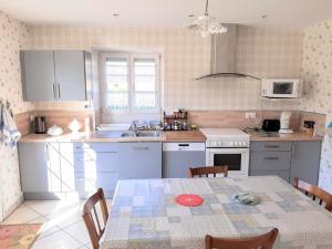 a kitchen with a table and chairs and a kitchen with white cabinets at Le Malmeix in Gerbécourt
