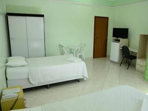 Schlafzimmer mit einem Bett, einem Schreibtisch und einem TV in der Unterkunft Hotel Mais in Macapá