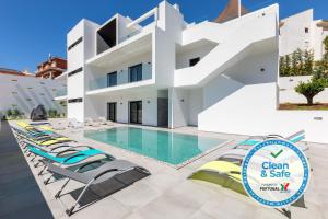 a villa with a swimming pool and lounge chairs at Luxury 47 in Albufeira