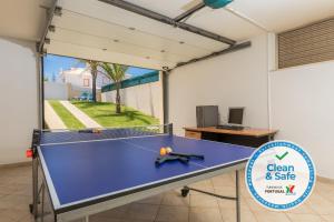 a ping pong table in a garage with a sign at Moradia Ricardo - Praia da Gale in Albufeira