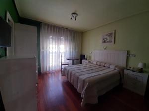 1 dormitorio con cama, mesa y ventana en Favila Oviedo, en Oviedo
