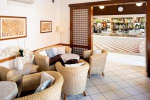 a lobby with wicker chairs and a bar in the background at Hotel Desiree in Lignano Sabbiadoro