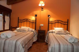 two beds in a bedroom with orange walls at Casa Rural EL VALLECILLO in Valle de Tabladillo