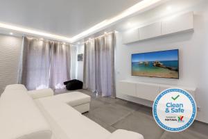 a white living room with a white couch and a tv at Luxury 47 in Albufeira