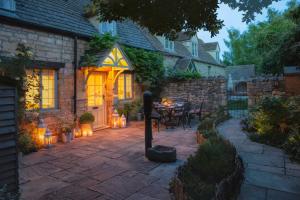 a patio with a table and lights in front of a house at Hook Cottage in Chipping Campden