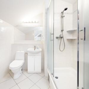 a white bathroom with a toilet and a shower at Willa Przy Plaży in Pogorzelica
