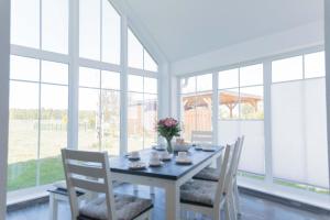 a dining room with a table and chairs and windows at Born - Wieck DAT SCHWEDENHUS EG-Whg. WI-4.1 in Wieck